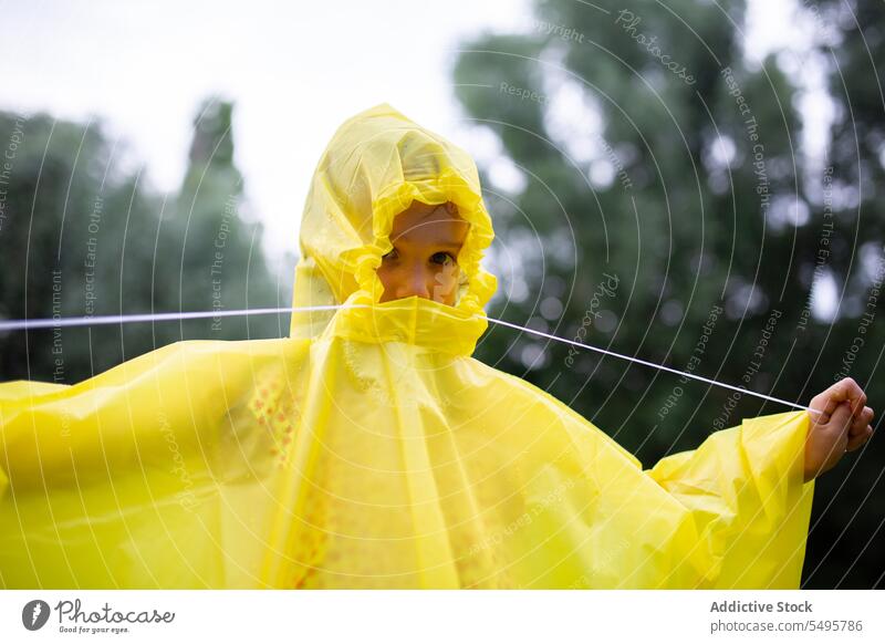 Girl in raincoat with cape child kid forest nature tree yellow weather woods environment childhood season stand protect anonymous green little plant wet