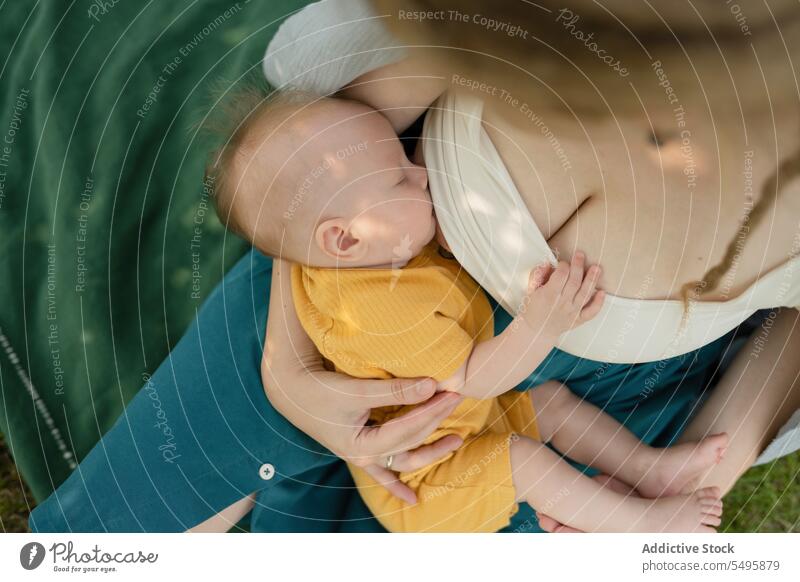 Woman breastfeeding baby while sitting in park mother woman milk care love infant maternal sleep postnatal eltern cute hug healthy motherhood suckle together