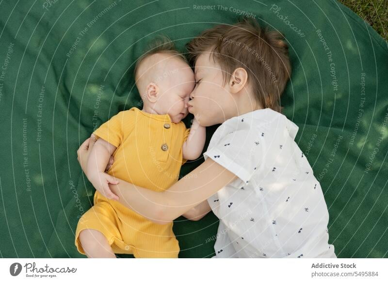 Cute brother with baby sibling lying on blanket in park kiss boy cute resting weekend together children lifestyle love childhood adorable little bonding