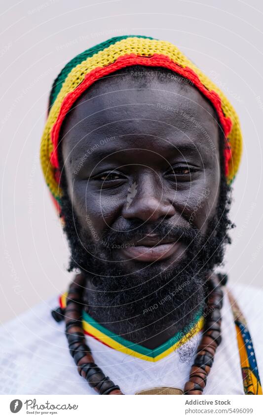 African American man in colorful hat standing and looking at camera african american ethnic crop clothing beard young black male white white background