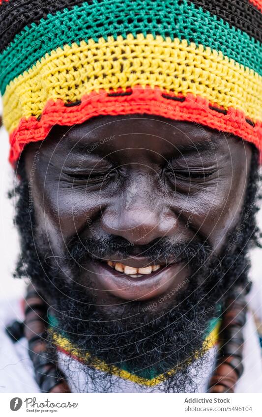 African American man in colorful hat standing with closed eyes african american ethnic crop clothing beard young black male white white background lifestyle