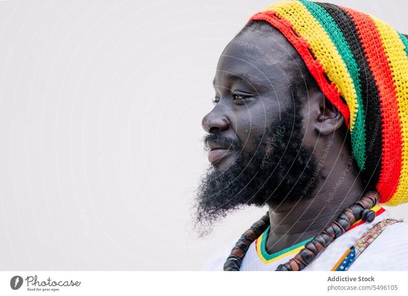 Side view of African American man in colorful hat standing and looking away african american ethnic side view crop clothing beard young black male white