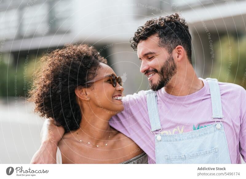 Cheerful multiethnic couple hugging on city street man woman walk smile happy relationship cheerful together bright bonding glad joy partner optimist positive