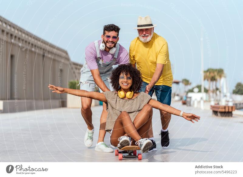 Joyful diverse friends having fun on city street ride skateboard cheerful smile urban happy together positive joy optimist glad town delight friendship content