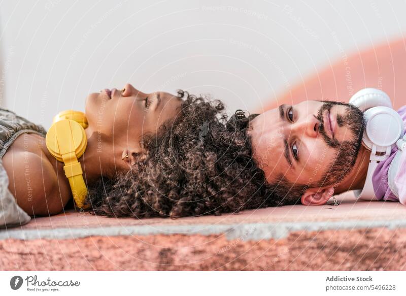 Young couple lying on floor with headphones relationship together relax apartment love lifestyle fondness affection romantic partner soulmate happy comfort