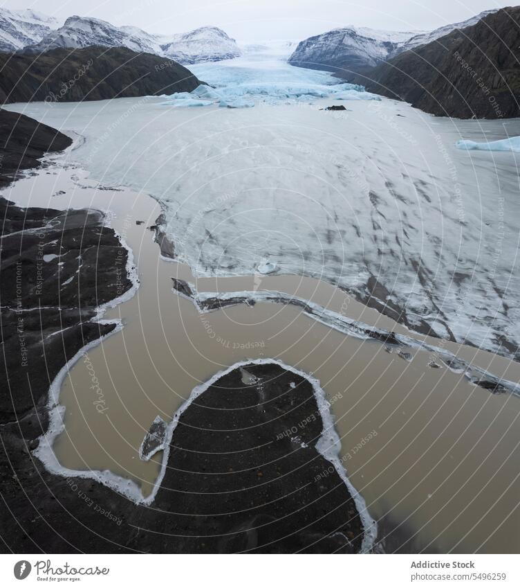 Drone view of frozen lake water between snowy mountains in daylight landscape scenery winter nature breathtaking blue sky cold environment daytime reflection