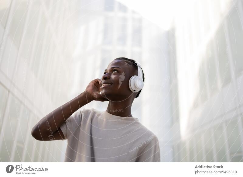 Black man in headphones dancing on street teenage music dance listen wireless move gadget urban positive young ethnic black african american device happy male