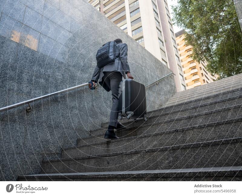 Anonymous black man with suitcase walking upstairs underground formal staircase stairway businessman male travel luggage african american baggage well dressed