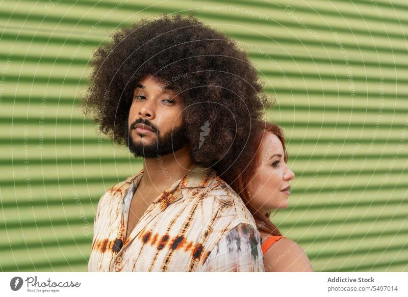 Multiracial couple standing back to back on green background soulmate relationship fondness bonding girlfriend portrait model studio afro curly hair hairstyle