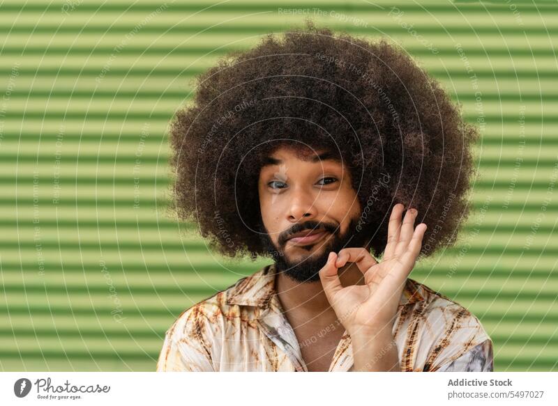 Smiling black man showing OK gesture against wall okay smile positive happy portrait sign glad cheerful male african american ethnic casual afro young