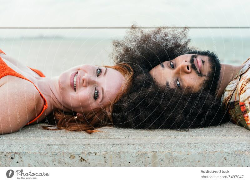 Smiling multiracial couple resting on concrete floor smile relationship spend time love fondness portrait happy diverse together bench friend romantic