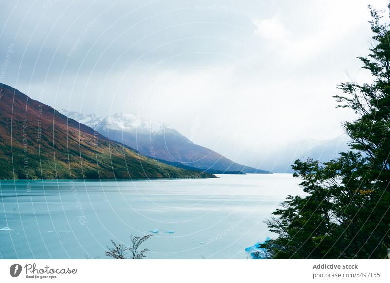 Snowy mountains near calm lake in cloudy day range landscape ridge glacier winter nature scenery ice blue sky snow cold scenic highland peak picturesque