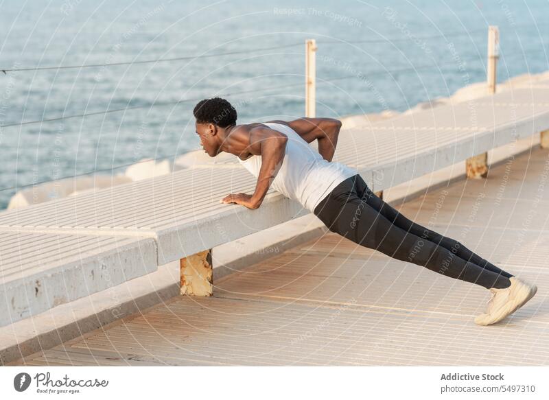 Black man doing push ups on embankment sea workout exercise sport sportswear water training male african american healthy effort waterfront activity physical