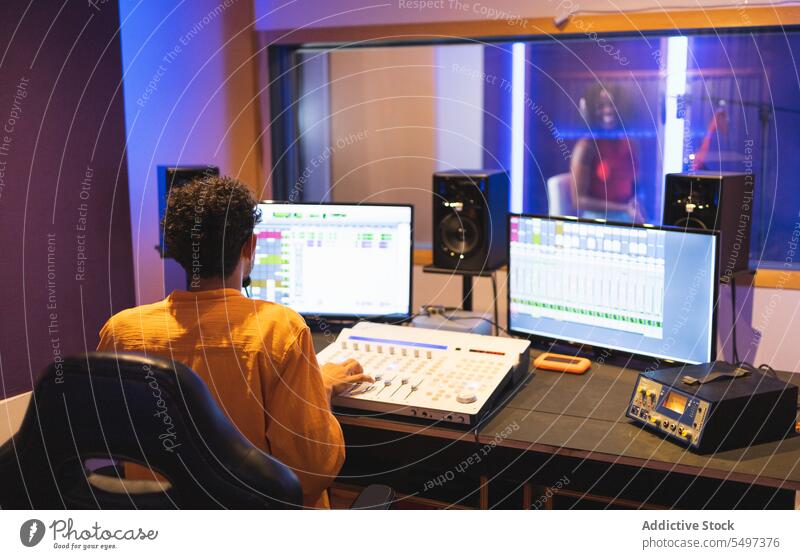 Man recording vocal in studio performer sing song audio engineer sound music black african american singer voice technician compose create produce industry