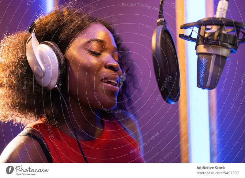 Black woman singing and creating song vocalist record create high note microphone headphones music studio female black african american professional singer star