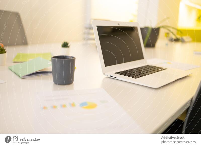 Laptop on desk in modern office laptop workplace cup workspace coffee netbook hot drink device gadget beverage table paper computer contemporary mug portable