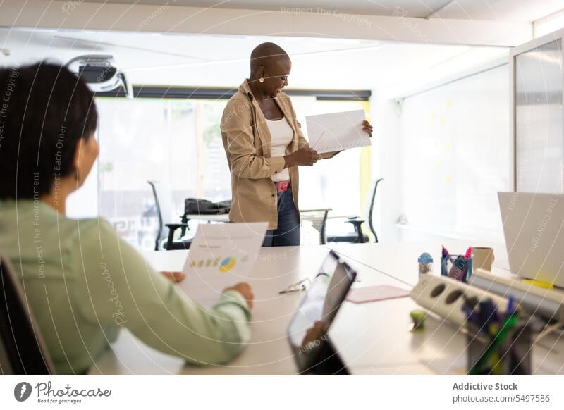 Colleague listening to a black woman speak colleague show paper coworker office workplace share meeting professional business workspace discuss teamwork