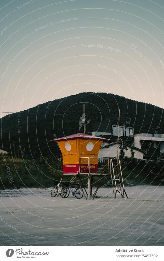 Old lifeguard hut on sandy beach in evening sunset seashore mountain rescue safety old fashioned south america brazil tower vintage retro bicycle control