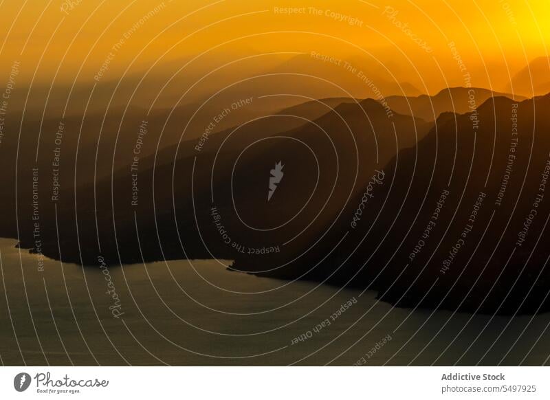 Lake and mountain formation during amazing sundown rocky ridge sunset landscape range silhouette nature Maggiore valley picturesque scenery environment orange