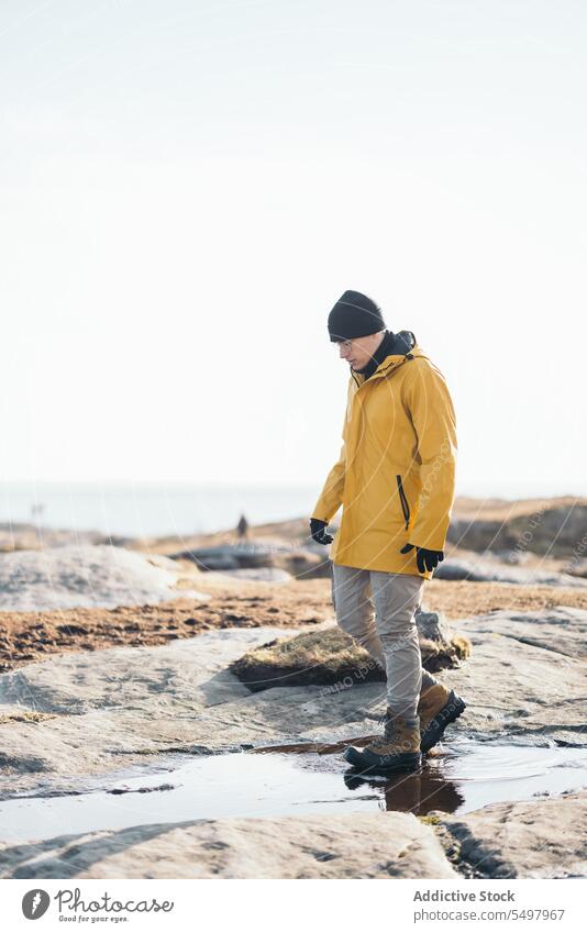 Man walking on puddle person boot stone footwear rough water ground wet environment reflection weather natural feet sunlight shadow shade aqua rocky liquid