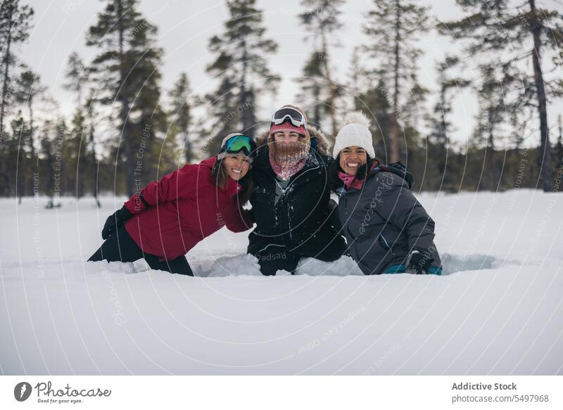 Happy women on snowy terrain in Lapland friend forest winter outerwear coniferous happy together smile female diverse multiracial multiethnic friendship