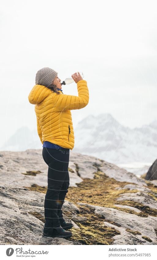 Woman traveler drinking water on rocky terrain woman tourist thirst bottle hiker adventure rough female trip outerwear mountain tourism beverage journey