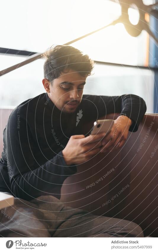 Young man using smartphone in waiting room at airport browsing passenger departure message trip connection mobile male device gadget modern lapland terminal