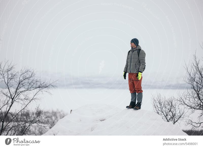 Smiling man standing on snowy terrain winter forest nature outerwear happy finland warm clothes cold cheerful tree woods woodland wintertime path joy season