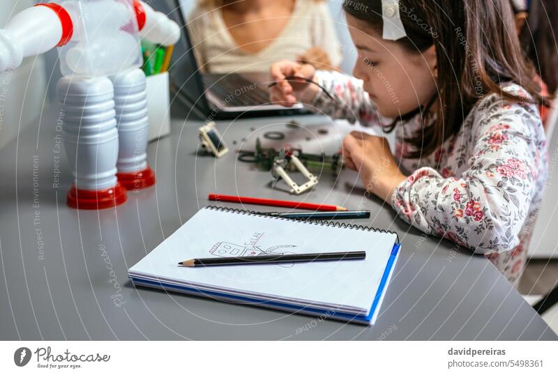 Robot draw by child on notebook and student connecting wire in electrical circuit on background children robot robotic female pencil colours paint solar panel