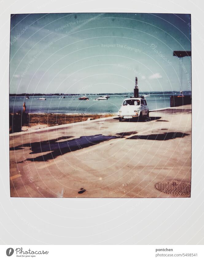 polaroid. a vintage car drives by the harbor. old, white, car Vintage car Harbour Driving Water boats Shadow Transport Lake Garda Italy Vacation & Travel Sky