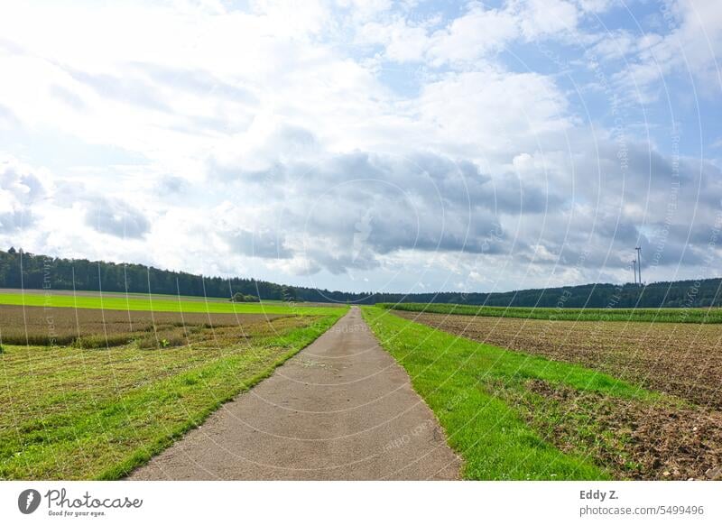 Clouds over fields and farmland. A road leads to the agricultural land. Lanes & trails Street Light Traffic infrastructure Deserted Day acre Field Agriculture