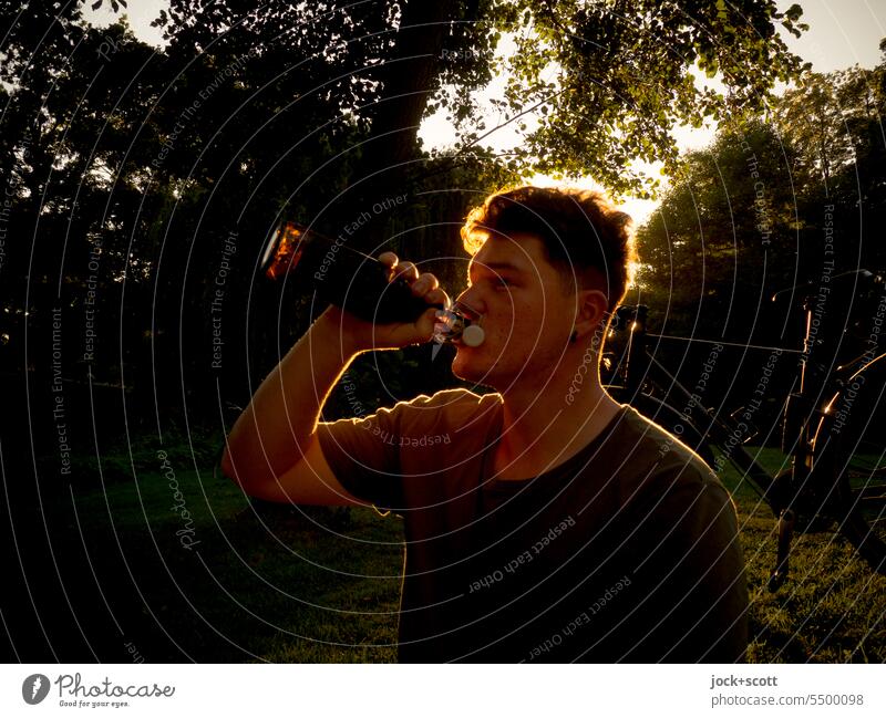 Young man finishes the sunny day with a beer Summer enjoyment Back-light Silhouette Drinking Thirst Alcoholic drinks To enjoy Refreshment Neutral Background