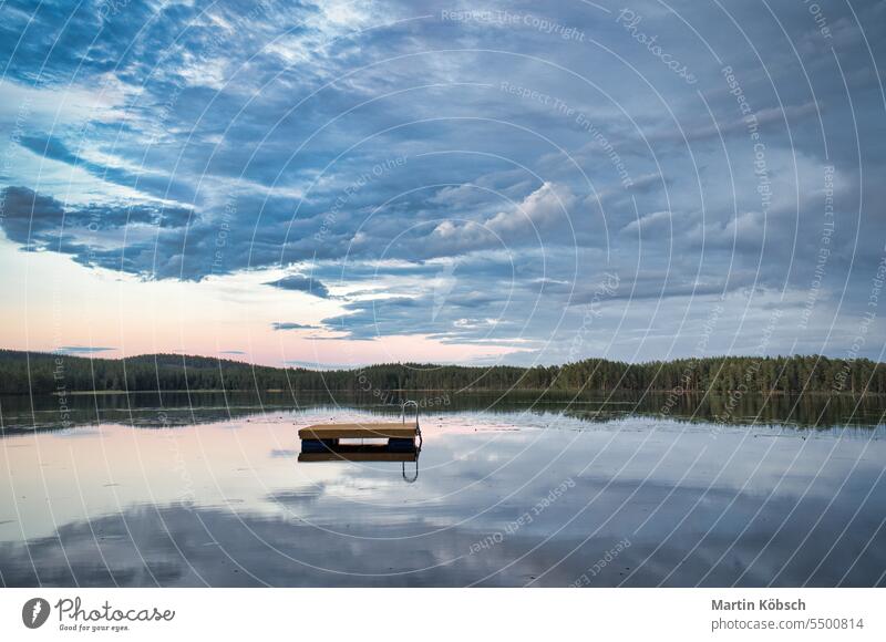 Swimming island in Sweden on a lake at sunset. Clouds reflected in the water. swimming island wooden island reflection summer vacation silence swimming fun