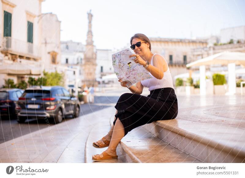 Female tourist with city map by the Saint Oronzo statue in Ostuni, Italy antique apulia architectonic architecture brindisi building column culture decorative