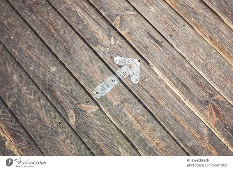 an arrow painted with white paint pointing to the top right on a wooden path Arrow Rising Right up Upward upward trend Woodway boards slats Wooden floor Sign