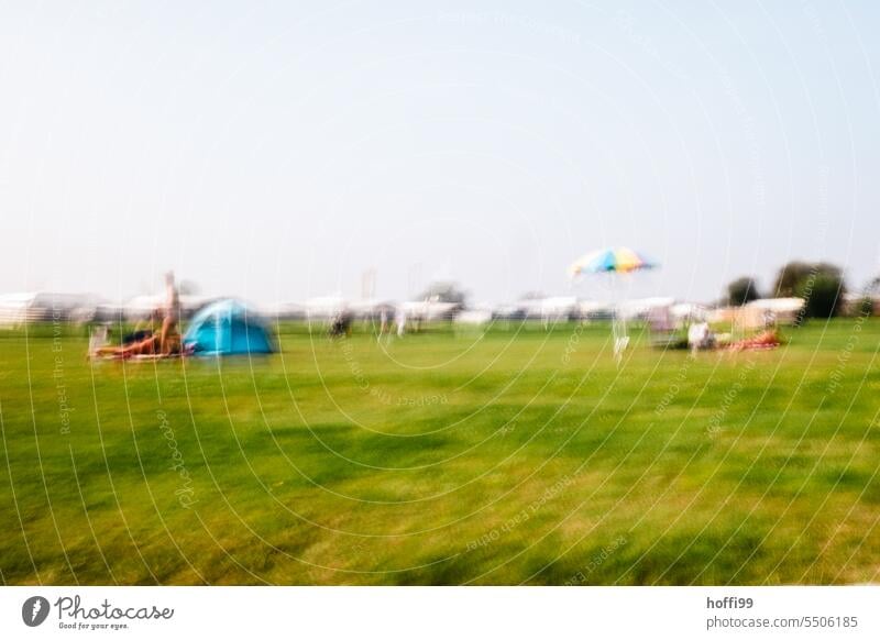 blurred view of very green sunbathing area in swimming pool or on beach with parasol and isolated people Sunshade Lawn for sunbathing lido Swimming pool Summer