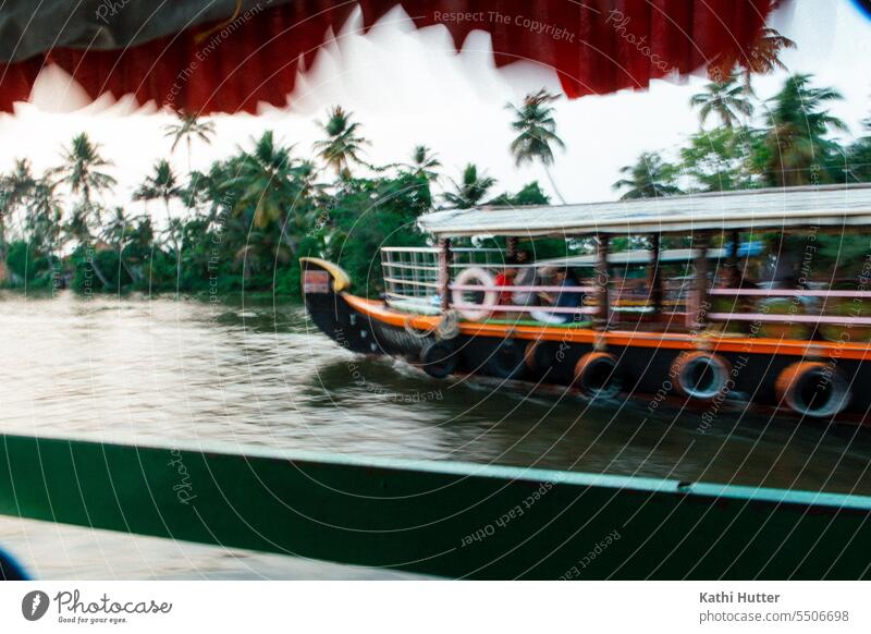 a boat passes another ship in the backwaters of Kerala. In the background you can see many palm trees. Navigation Exterior shot Harbour Water Dew Blue