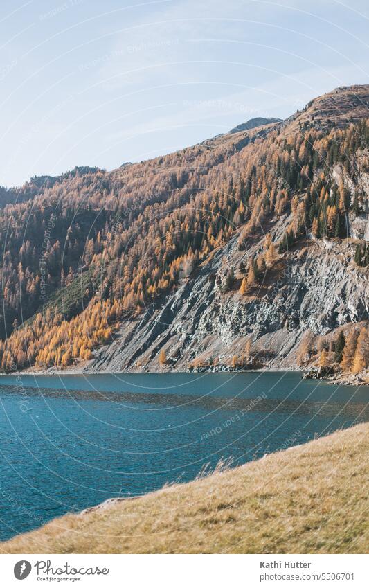 a blue lake with a mountain in the background which has many fir trees in autumn colors. Lake mountain lake Nature Landscape Mountain Exterior shot Water