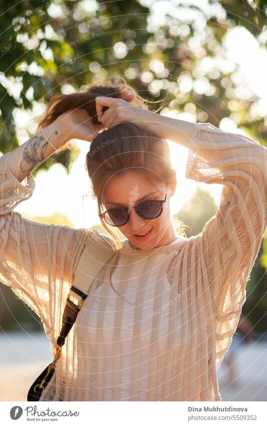 candid portrait of young beautiful woman in sunglasses backlit with sunlight in summer. Pretty ginger girl with red hair. park smiling happy pretty Smiling