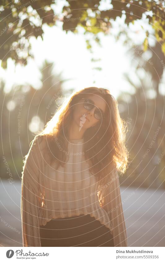 candid portrait of young beautiful woman in sunglasses backlit with sunlight in summer. Pretty ginger girl with red hair. park smiling happy pretty Smiling