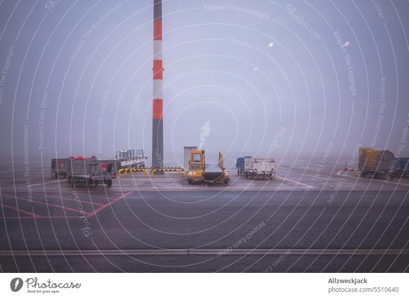 Suitcase trolleys standing in dense fog on airport tarmac Fog Shroud of fog Wall of fog Weather Soup tight opaque sight Airport Runway box van Still Life
