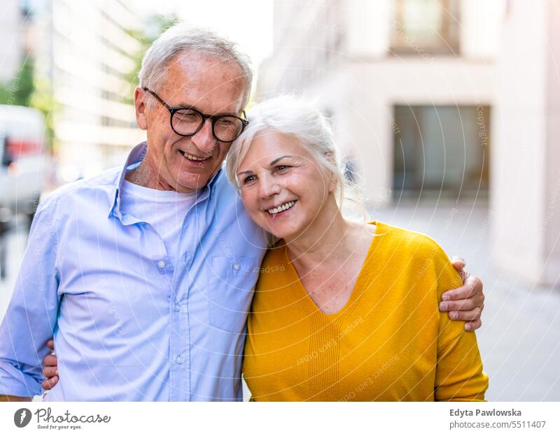 Portrait of a happy senior couple embracing in the city people caucasian standing healthy city life gray hair enjoy street casual day portrait outside