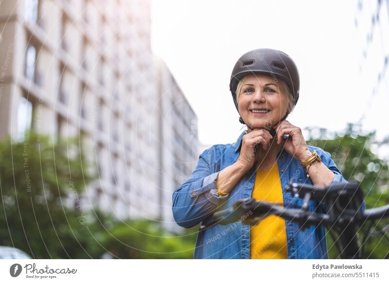 Portrait of senior woman wearing helmet while riding bicycle in the city people caucasian standing healthy city life gray hair enjoy street casual day portrait