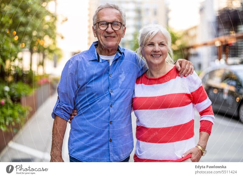 Portrait of a happy senior couple embracing in the city people caucasian standing healthy city life gray hair enjoy street casual day portrait outside