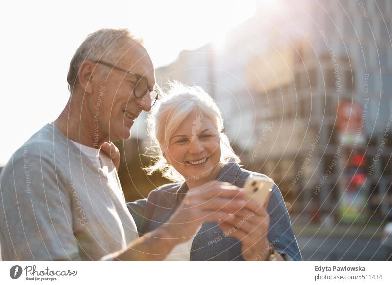 Senior couple using smartphone in the city people caucasian standing healthy city life gray hair enjoy street casual day portrait outside real people