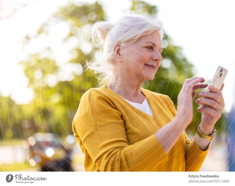 Senior woman using smartphone outdoors people caucasian standing healthy city life gray hair enjoy street casual day portrait outside real people white people