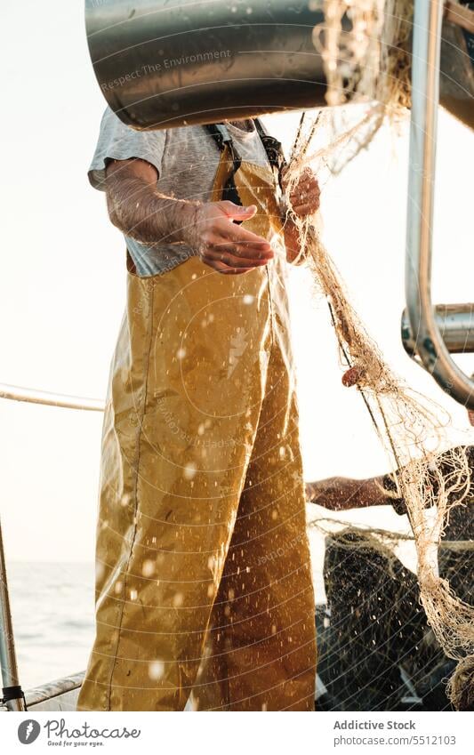 Anonymous fisherman fishing in open sea from sail boat net schooner work uniform focus male soller balearic islands mallorca seine fish hunt trawler