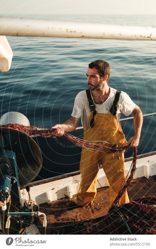 Fisherman fishing in open sea from sail boat fisherman net schooner work uniform focus male soller balearic islands mallorca seine fish hunt trawler