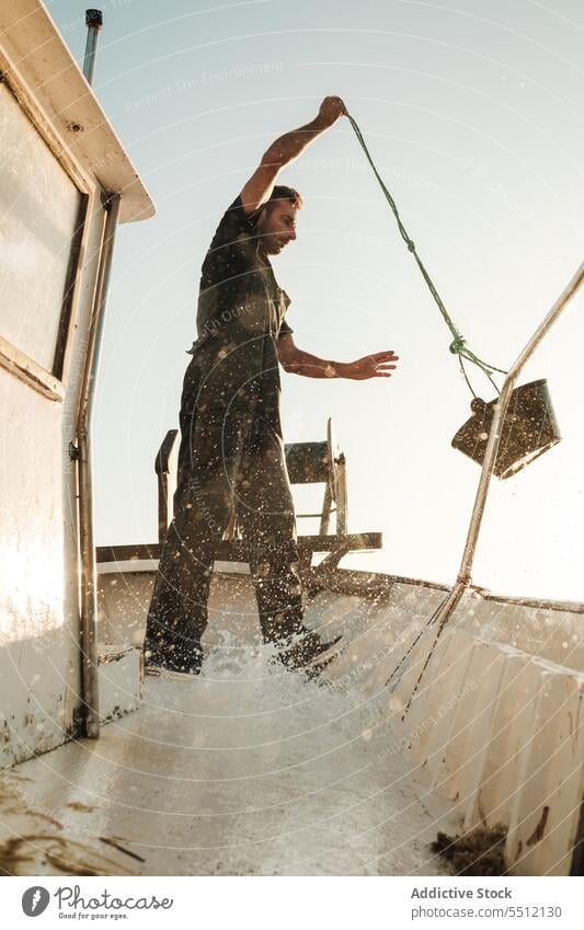 Seaman cleaning deck of fishing boat seaman fisher schooner pour water bucket male soller balearic islands mallorca fisherman sailor tradition seine fish net