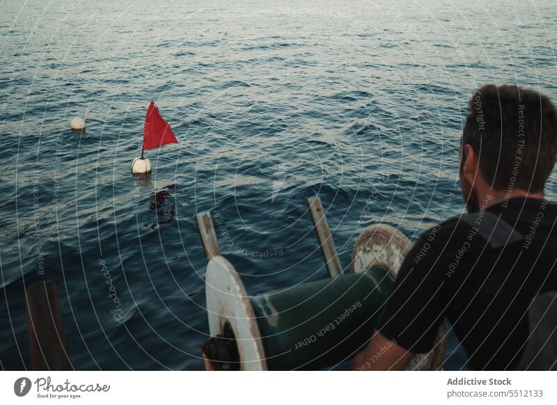 Unrecognizable man standing on boat and floating buoys on seawater flag lifesaver ripple vessel wheel male lifeguard rescue lifebuoy transport marine guy wave